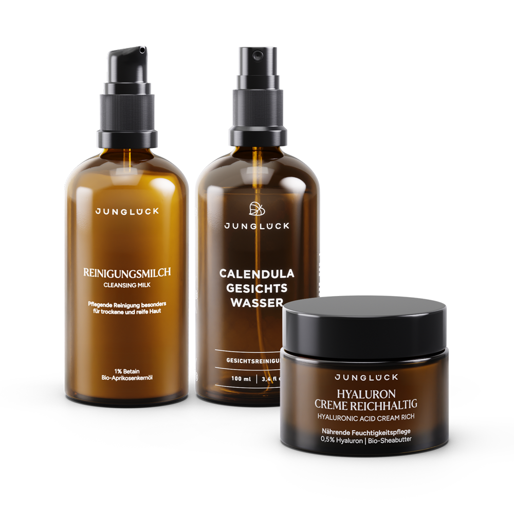 Set of three brown glass skincare bottles labeled Junglück with black pumps and lids, including cleansing milk, calendula.
