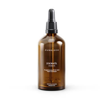 Amber glass bottle of alcohol-free jojoba oil with black pump dispenser and minimalist white label text.
