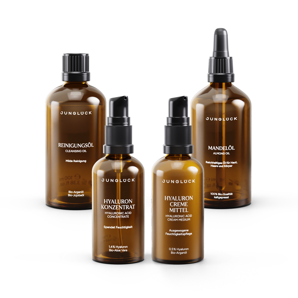 Four brown glass skincare bottles with black caps and white labels, including cleansing oil, hyaluronic concentrate,.