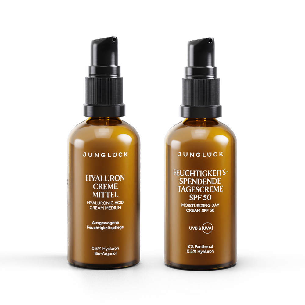 Zwei Braunglasflaschen von JUNGLÜCK: Hyaluron Creme Mittel und Feuchtigkeitsspendende Tagescreme SPF 50.