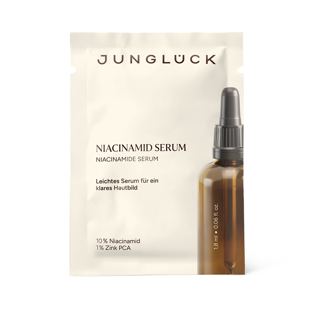 Small beige sachet labeled Jungluck Niacinamid Serum next to amber dropper bottle with dark cap.