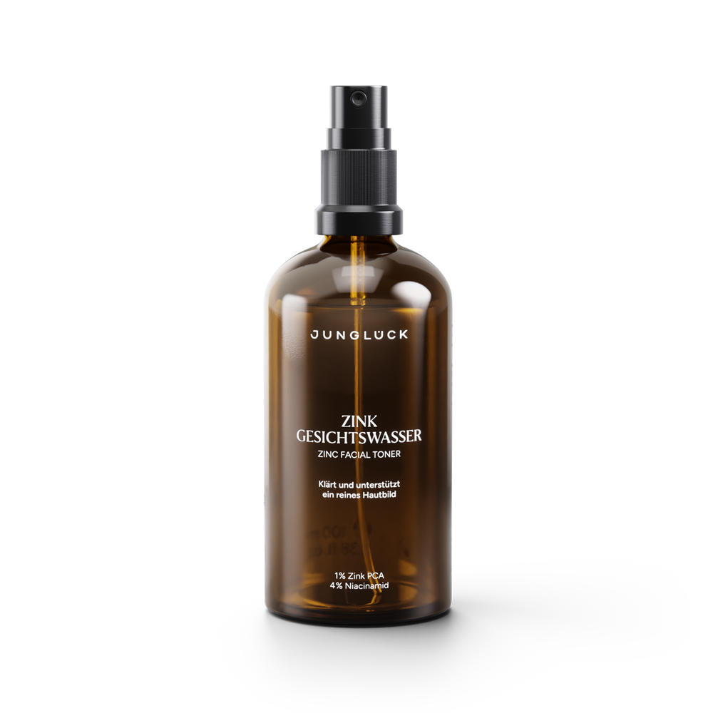 Amber glass spray bottle of Junglück Zink Gesichtswasser facial toner with black pump and white label text.