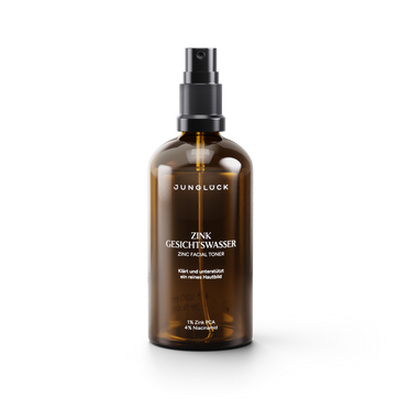 Amber glass spray bottle of Junglück Zink Gesichtswasser facial toner with black pump and white label text.